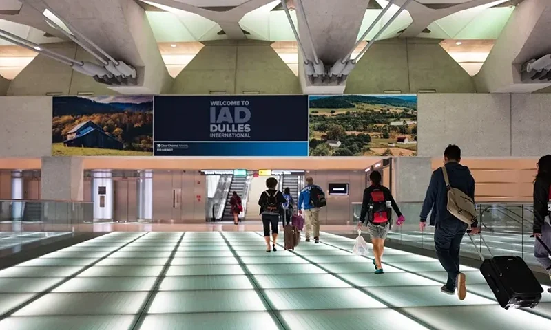 Passengers pull their rolling suitcases across a lighted glass bridge at Dulles International Airport in Dulles, Virginia, on Sept. 24, 2016. (Smith Collection/Gado/Getty Images)