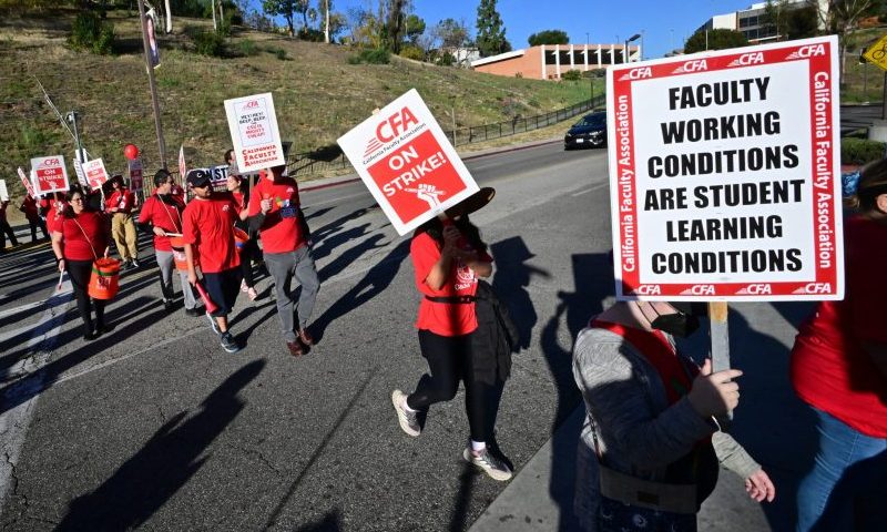 Members of the faculty union of the California State University system, as well as supporters, carry signs while walking the picket line during a one day strike at California State University-Los Angeles in Los Angeles, California, on December 6, 2023. Employees are looking for a twelve percent raise during a series of four one-day strikes taking place on college campuses across the state of California. (Photo by Frederic J. BROWN / AFP) (Photo by FREDERIC J. BROWN/AFP via Getty Images)