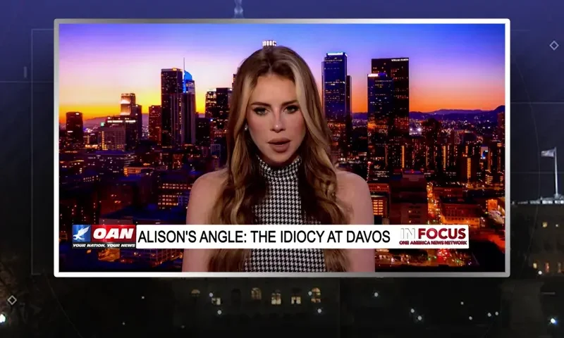 Video still of the host of In Focus at the desk of their talk show on One America News Network.