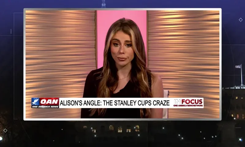 Video still of the host of In Focus at the desk of their talk show on One America News Network.