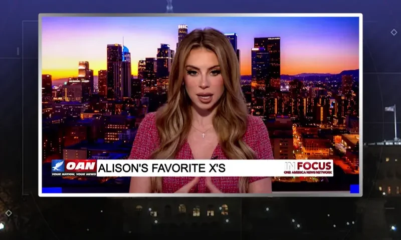 Video still of the host of In Focus at the desk of their talk show on One America News Network.