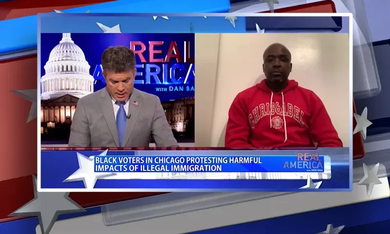 Video still from Real America on One America News Network showing a split screen of the host on the left side, and on the right side is the guest, Mark Carter.