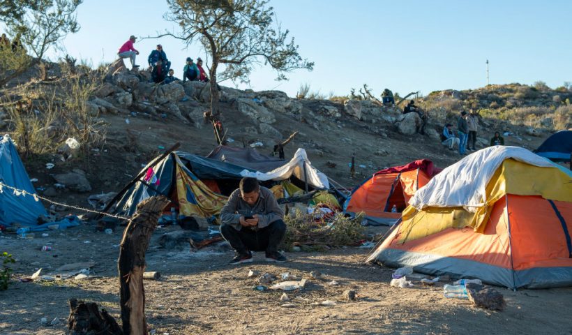 A Chinese migrant sit in front of his tent near the US-Mexico border fence in Jacumba, California, on December 6, 2023. Hundreds of migrants who cross into the United States each day are being herded into open-air camps, where they have no access to food or water, with some are left to sleep on the open ground in a desert riddled with scorpions and snakes, activists say. (Photo by VALERIE MACON / AFP) (Photo by VALERIE MACON/AFP via Getty Images)