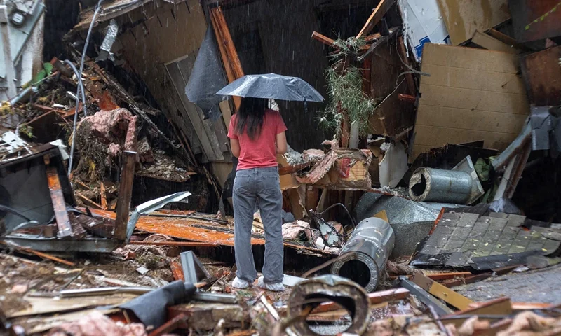 TOPSHOT-US-WEATHER-STORM-CALIFORNIA-FLOODING TOPSHOT - A woman stands among the wreckage of a house that was abruptly destroyed by a landslide as a historic atmospheric river storm inundates the Hollywood Hills area of Los Angeles, California, on February 6, 2024. A powerful storm lashing California has left at least three people dead and caused devastating mudslides and flooding, after dumping months' worth of rain in a single day. (Photo by DAVID MCNEW / AFP) (Photo by DAVID MCNEW/AFP via Getty Images)