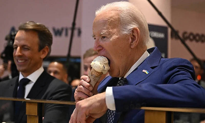 TOPSHOT - US President Joe Biden (R), flanked by host Seth Meyers (L), eats an ice cream cone at Van Leeuwen Ice Cream after taping an episode of "Late Night with Seth Meyers" in New York City on February 26, 2024. (Photo by Jim WATSON / AFP) (Photo by JIM WATSON/AFP via Getty Images)