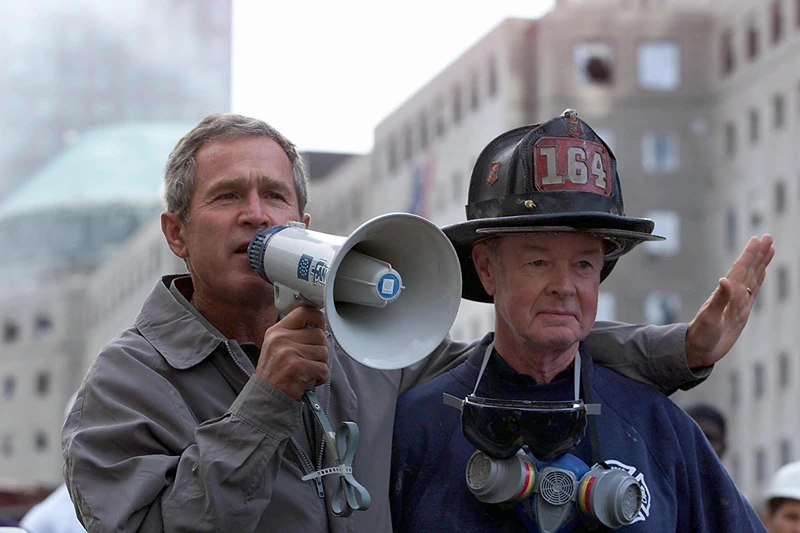 US President George W. Bush (L), standing next to
NEW YORK, NY - SEPTEMBER 14: US President George W. Bush (L), standing next to retired firefighter Bob Beckwith, 69, speaks to volunteers and firemen as he surveys the damage at the site of the World Trade Center in New York in this 14 September 2001 file photo. Bush was presented with the same bullhorn he used to address the rescue workers in this photo at a ceremony 25 February 2002 in the Oval Office of the White House in Washington, DC which was attended by Beckwith and New York Governor George Pataki. The President said the bullhorn would be put on display at his father's Presidential Library. (Photo credit should read PAUL RICHARDS/AFP via Getty Images)