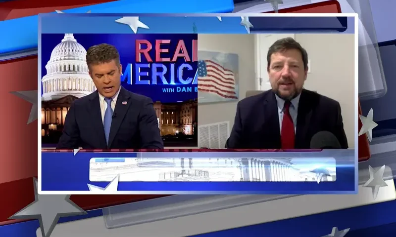Video still from Real America on One America News Network showing a split screen of the host on the left side, and on the right side is the guest, Ed Martin.