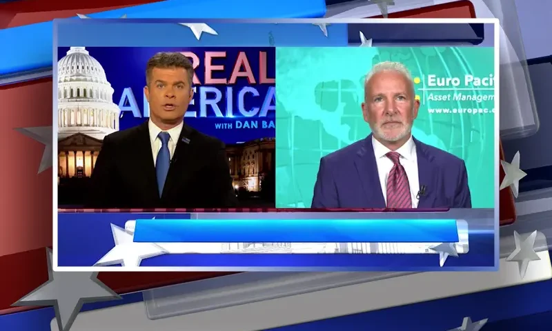 Video still from Real America on One America News Network showing a split screen of the host on the left side, and on the right side is the guest, Peter Schiff.