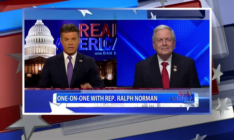 Video still from Real America on One America News Network showing a split screen of the host on the left side, and on the right side is the guest, Rep. Ralph Norman.
