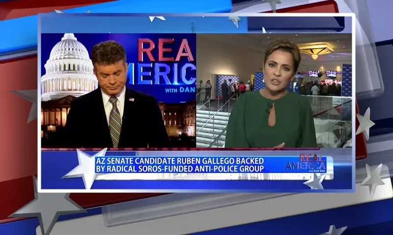 Video still from Real America on One America News Network showing a split screen of the host on the left side, and on the right side is the guest, Kari Lake.