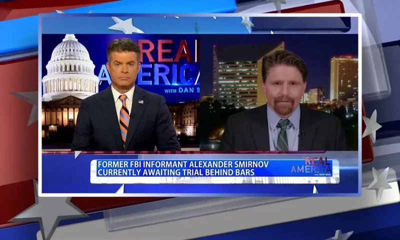 Video still from Real America on One America News Network showing a split screen of the host on the left side, and on the right side is the guest, Seamus Bruner.