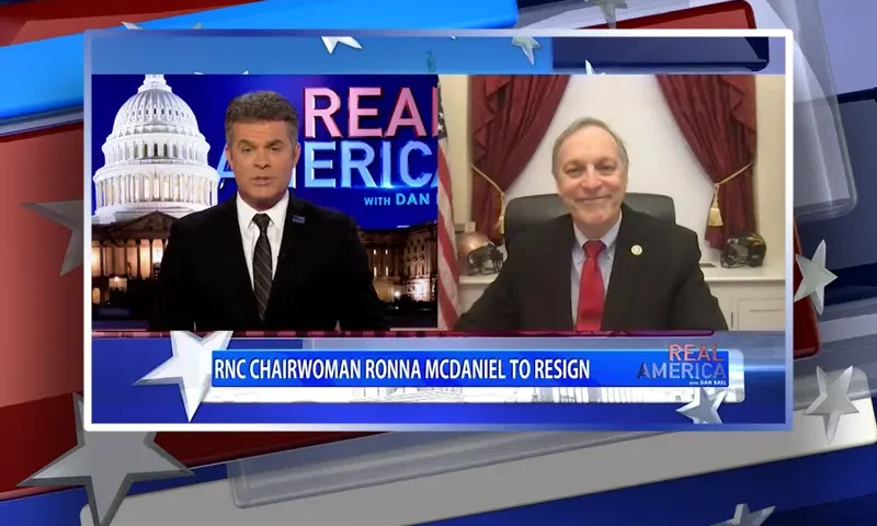 Video still from Real America on One America News Network showing a split screen of the host on the left side, and on the right side is the guest, Rep. Andy Biggs.