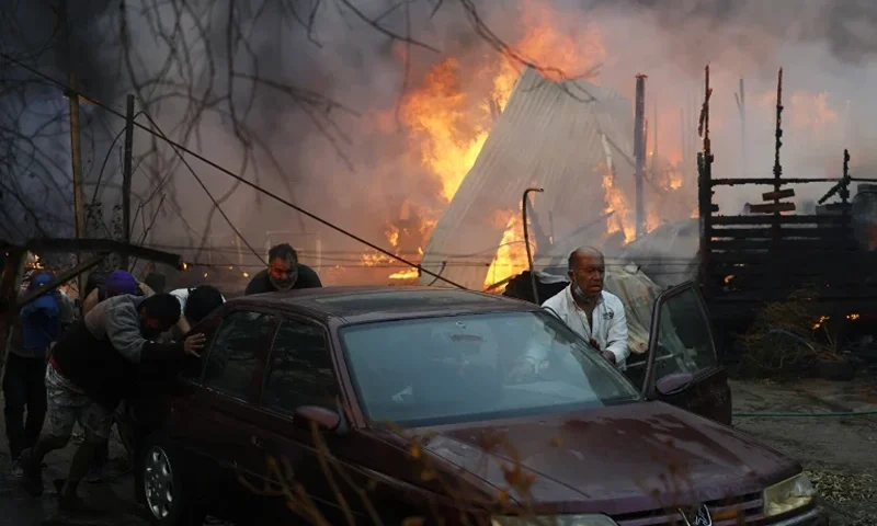 3 of 10 | Residents push a car away from a burning forest fire engulfing homes in Villa Alemana, Valparaiso, Chile, Friday, Feb. 2, 2024. (Andres Pina, Aton Chile via AP)