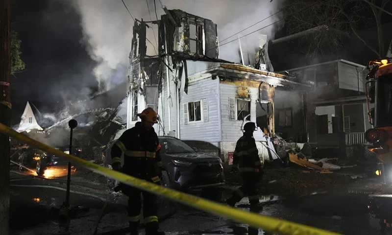 Firefighters work at the scene where two police officers were injured while responding to reported standoff in East Lansdowne, Pa., on Wednesday, Feb. 7, 2024. (AP Photo/Matt Rourke)