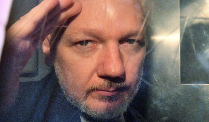 TOPSHOT - WikiLeaks founder Julian Assange gestures from the window of a prison van as he is driven out of Southwark Crown Court in London on May 1, 2019, after having been sentenced to 50 weeks in prison for breaching his bail conditions in 2012. - A British judge on Wednesday sentenced WikiLeaks founder Julian Assange to 50 weeks in prison for breaching his bail conditions in 2012. Assange took refuge in Ecuador's London embassy to avoid extradition to Sweden and was only arrested last month after Ecuador withdrew his asylum status. (Photo by Daniel LEAL / AFP) (Photo by DANIEL LEAL/AFP via Getty Images)