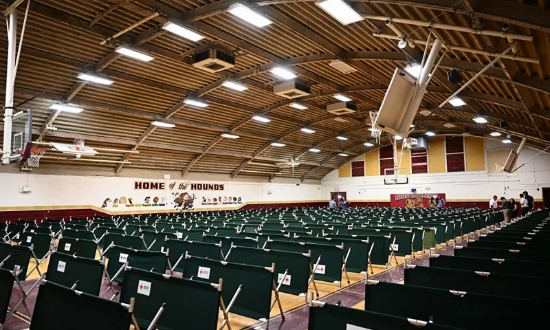 Reporters view cots arranged in a temporary shelter set up for processed migrants at the former Bassett Middle School in El Paso, Texas on May 10, 2023. The shelter is built by the city's Office of Emergency Management in coordination with the Red Cross for migrants after they cross the border and have been processed by the US Customers and Border Protection (CBP) for immigration and asylum claims. The US on May 11, 2023, will officially end its 40-month Covid-19 emergency, also discarding the Title 42 law, a tool that has been used to prevent millions of migrants from entering the country. (Photo by Patrick T. Fallon / AFP) (Photo by PATRICK T. FALLON/AFP via Getty Images)