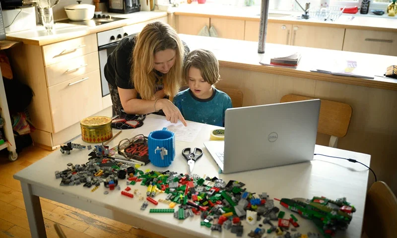 LONDON, UNITED KINGDOM - JANUARY 25: James Laurie, aged 8, is assisted in his online work by his mother Laurette as he continues home schooling, on January 25, 2021 in London, United Kingdom. Under current government policy, schools in England wouldn't open before the February half-term break at the earliest, but the prime minister has declined to commit to reopening them before Easter. (Photo by Leon Neal/Getty Images)