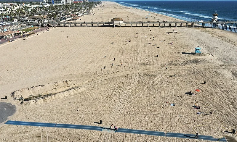HUNTINGTON BEACH, CALIFORNIA - OCTOBER 09: In an aerial view, few people gather along the beach about one week after an oil spill from an offshore oil platform on October 9, 2021 in Huntington Beach, California. The heavy crude oil spill affected close to 25 miles of coastline in Orange County. Huntington Beach is open but the public is not allowed to enter the water. (Photo by Mario Tama/Getty Images)