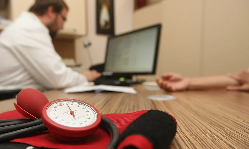 BERLIN, GERMANY - SEPTEMBER 05: A doctor speaks to a patient as a sphygmomanometer, or blood pressure meter, lies on his desk on September 5, 2012 in Berlin, Germany. Doctors in the country are demanding higher payments from health insurance companies (Krankenkassen). Over 20 doctors' associations are expected to hold a vote this week over possible strikes and temporary closings of their practices if assurances that a requested additional annual increase of 3.5 billion euros (4,390,475,550 USD) in payments are not provided. The Kassenaerztlichen Bundesvereinigung (KBV), the National Association of Statutory Health Insurance Physicians, unexpectedly broke off talks with the health insurance companies on Monday. (Photo by Adam Berry/Getty Images)