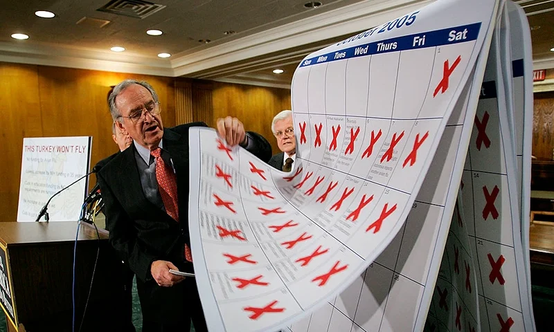 WASHINGTON - NOVEMBER 17: Sen. Tom Harkin lifts pages of a calendar he said represented inaction on the part of the Bush administration during a press conference highlighting the removal of funding for avian flu preparedness and the "lack of adequate resources" in the Labor, Health and Human Services Appropriations conference report November 17, 2005 on Capitol Hill in Washington, DC. Joining Harkin were Sen. Ted Kennedy (D-MA) (R) and Sen. Richard Durbin (D-IL) (L-obscured). (Photo by Win McNamee/Getty Images)