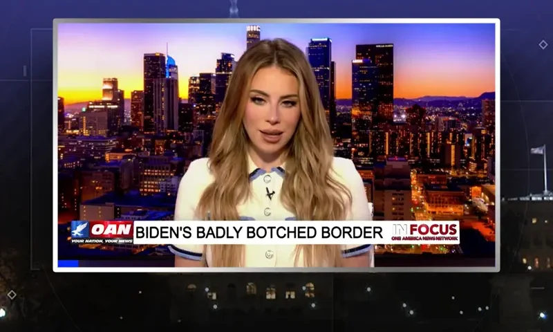 Video still of the host of In Focus at the desk of their talk show on One America News Network.