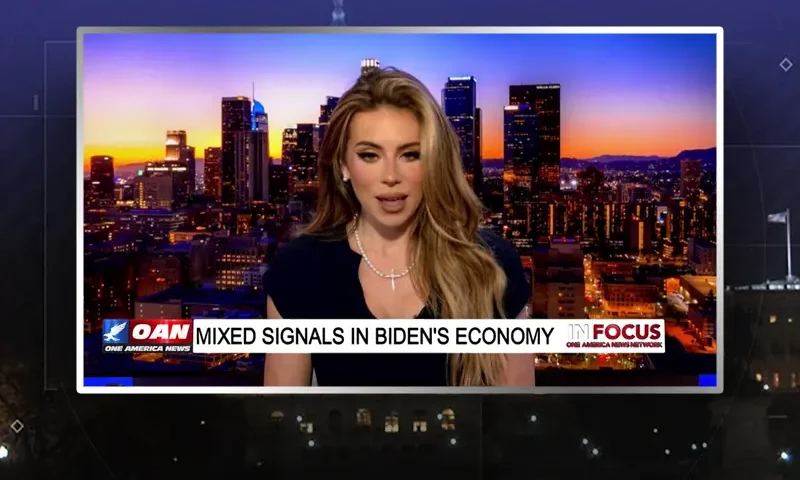 Video still of the host of In Focus at the desk of their talk show on One America News Network.