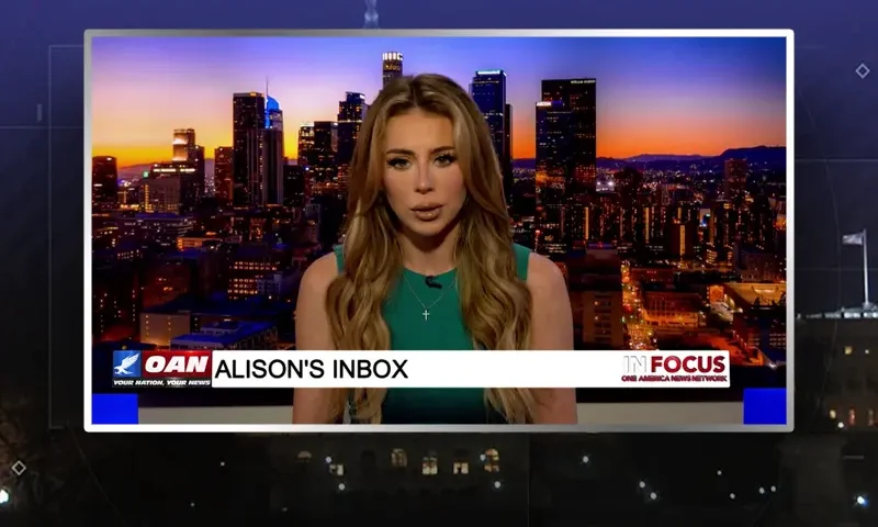 Video still of the host of In Focus at the desk of their talk show on One America News Network.