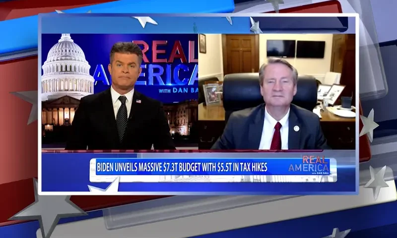 Video still from Real America on One America News Network showing a split screen of the host on the left side, and on the right side is the guest, Rep. Tim Burchett.
