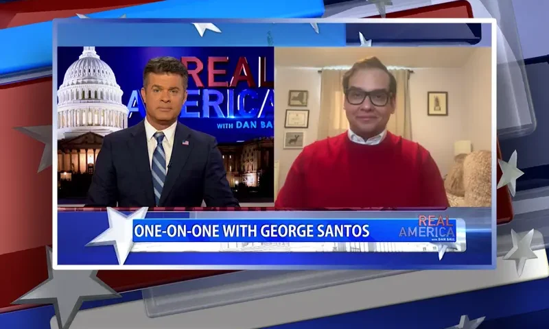 Video still from Real America on One America News Network showing a split screen of the host on the left side, and on the right side is the guest, George Santos.