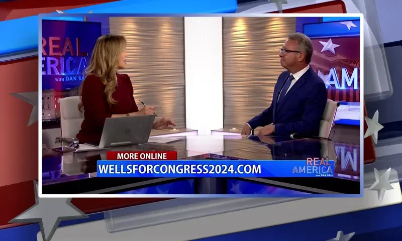 Video still from Real America on One America News Network showing the host on the left side, and on the right side is the guest, Bill Wells.