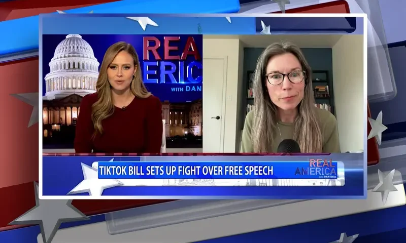 Video still from Real America on One America News Network showing a split screen of the host on the left side, and on the right side is the guest, Amy Peikoff.