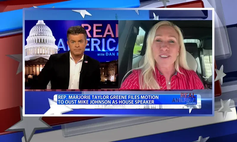 Video still from Real America on One America News Network showing a split screen of the host on the left side, and on the right side is the guest, Rep. Marjorie Taylor Greene.