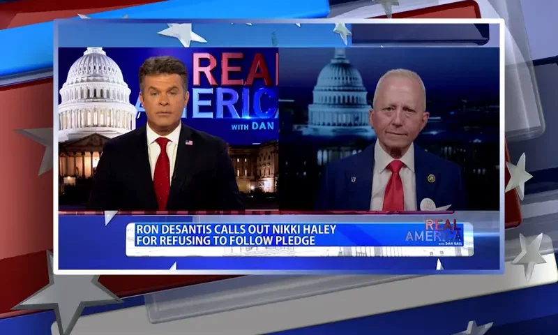 Video still from Real America on One America News Network showing a split screen of the host on the left side, and on the right side is the guest, Jeff Van Drew.