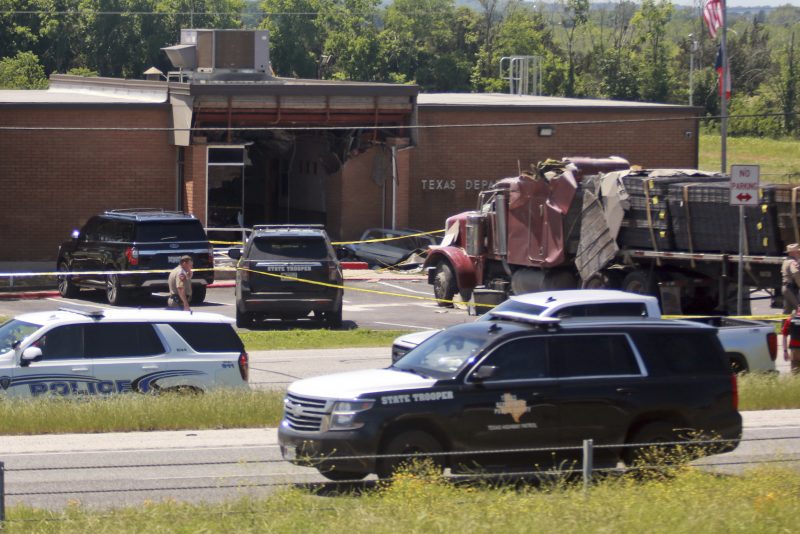 Emergency personnel work at the scene after an 18-wheeler crashed into the Texas Department of Public Safety Office in Brenham, Texas, Friday, April 12, 2024. A suspect is in custody in connection to a commercial vehicle crash at the Texas Department of Public Safety office in the rural town west of Houston. Texas DPS officials say multiple injuries were reported in the crash. (AP Photo/Lekan Oyekanmi)