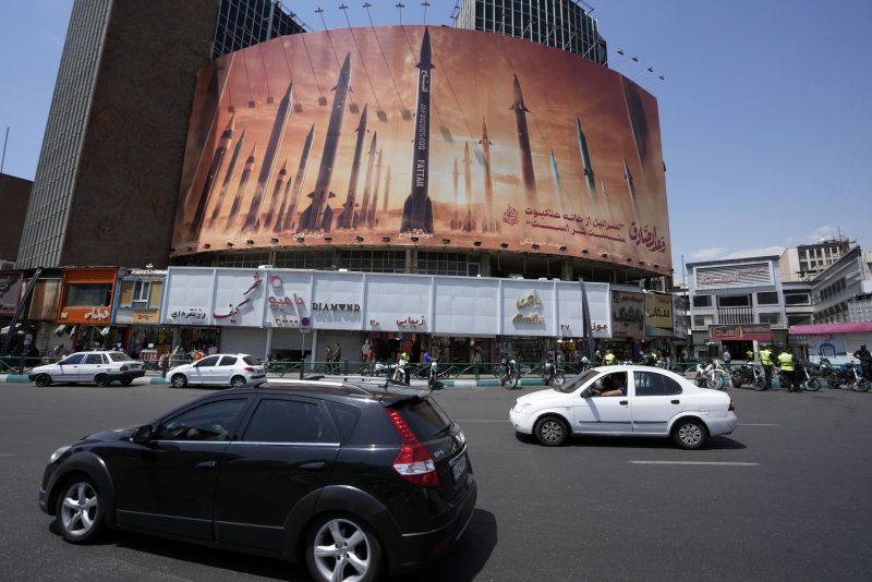 Vehicles drive past an anti-Israeli banner showing missiles being launched, in a square in downtown Tehran, Iran, Friday, April 19, 2024. Iran fired air defenses at a major air base and a nuclear site near the central city of Isfahan after spotting drones early Friday morning, raising fears of a possible Israeli strike in retaliation for Tehran's unprecedented drone-and-missile assault on the country. (AP Photo/Vahid Salemi)
