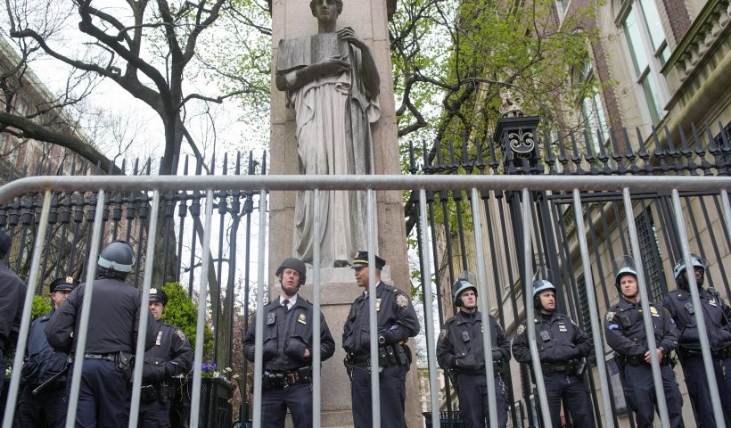 FILE - New York City police in riot gear stand guard outside the Columbia University campus after clearing the campus of protesters, April 18, 2024, in New York. Columbia University canceled in-person classes Monday, April 22, 2024 and police arrested several dozen protesters at Yale University as tensions on U.S. college campuses continue to grow over the war in the Middle East. (AP Photo/Mary Altaffer, file)