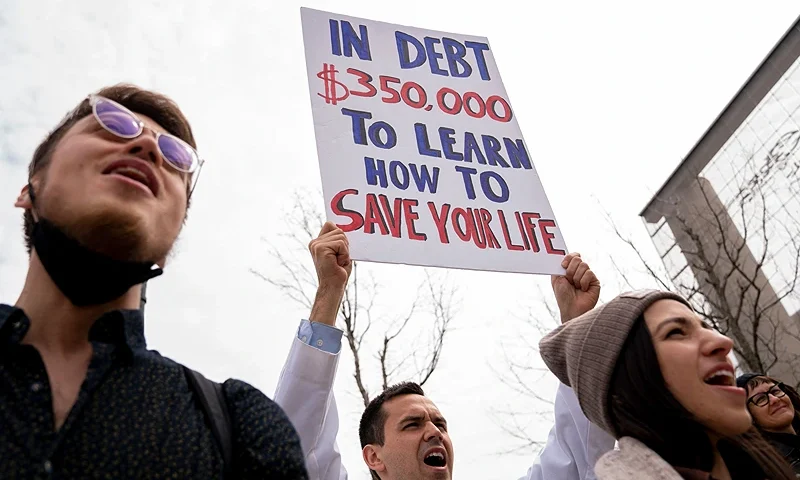 People hold signs during a Cancel Student Debt rally outside the US Department of Education in Washington, DC, on April 4, 2022. - Demonstrators gathered to call on US President Joe Biden to wipe out all student debt, as the student loan payment pause, put into place during the Covid-19 pandemic, is set to expire on May 1. (Photo by Stefani Reynolds / AFP) (Photo by STEFANI REYNOLDS/AFP via Getty Images)