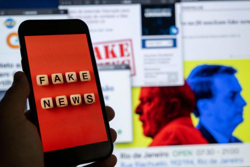 This illustration picture shows a smart phone screen displaying the phrase "Fake News" in front of a desktop screen showing several news and research reports about fake news and disinformation related to the upcoming Brazilian presidential election, in Rio de Janeiro, Brazil, on August 29, 2022. - The sheer volume of fake news, creation of new social media platforms and ever more complex content has made it even more difficult to verify information ahead of the October 2 presidential elections. (Photo by Mauro PIMENTEL / AFP) (Photo by MAURO PIMENTEL/AFP via Getty Images)