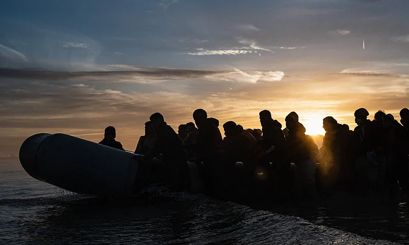 TOPSHOT - Migrants board a smuggler's boat on the beach of Gravelines, near Dunkirk, northern France on October 12, 2022, in a attempt to cross the English Channel. (Photo by Sameer Al-DOUMY / AFP) (Photo by SAMEER AL-DOUMY/AFP via Getty Images)
