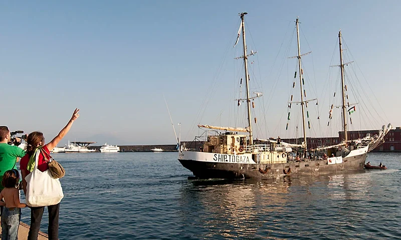 Supporters of sailship Estelle waves to the crew as the ship leaves from Naples heading for Gaza in the port of Naples on October 6, 2012. The Estelle, the latest ship to try to break Israel's blockade on Gaza as part of the "Freedom Flotilla" movement, is to set sail from Naples in southern Italy today. The Estelle, whose voyage is being organized by an international pro-Palestinian coalition, will be carrying humanitarian goods to the Gaza Strip. There will be 17 activists from around the world on board, including passengers and crew from Canada, Israel, Norway, Sweden and the United States. AFP PHOTO / MADDALENA TARTARO (Photo credit should read MADDALENA TARTARO/AFP/GettyImages)
