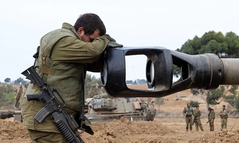 TOPSHOT - An Israeli soldier rests his head on the gun barrel of a self-propelled artillery howitzer as Israeli soldiers take positions near the border with Gaza in southern Israel on October 9, 2023. One month after Israel was wracked by Hamas attacks, life has been upended for both the Palestinians and Israel after it launched a war of reprisal in the Gaza Strip. The October 7 attacks by Hamas militants who stormed across from Gaza and struck kibbutzim and southern Israeli areas killed 1,400 people, mostly civilians, and deeply scarred the nation. The health ministry in Hamas-run Gaza says nearly 9,500 have been killed, two-thirds of them women and children, and mostly civilians. (Photo by JACK GUEZ / AFP) (Photo by JACK GUEZ/AFP via Getty Images)