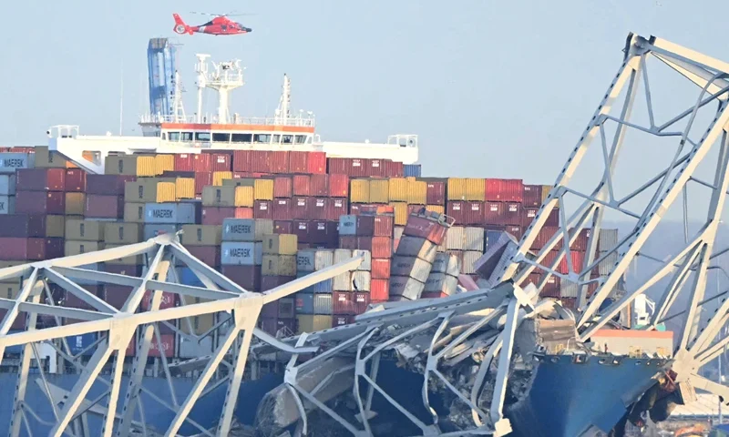 TOPSHOT-US-TRANSPORT-INCIDENT TOPSHOT - The steel frame of the Francis Scott Key Bridge sit on top of a container ship after the bridge collapsed in Baltimore, Maryland, on March 26, 2024. The bridge collapsed after being struck by a container ship, sending multiple vehicles and up to 20 people plunging into the harbor below. "Unfortunately, we understand that there were up to 20 individuals who may be in the Patapsco River right now as well as multiple vehicles," Kevin Cartwright of the Baltimore Fire Department told CNN. Ship monitoring website MarineTraffic showed a Singapore-flagged container ship called the Dali stopped under the bridge. (Photo by Mandel NGAN / AFP) (Photo by MANDEL NGAN/AFP via Getty Images)