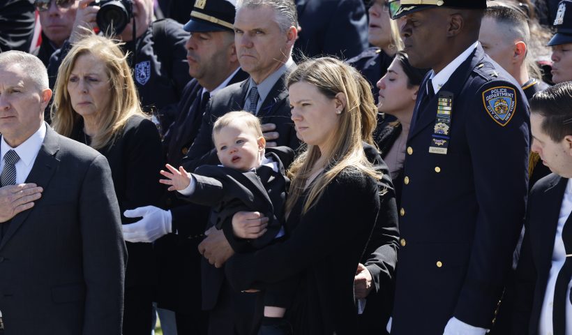 MASSAPEQUA, NEW YORK - MARCH 30: Stephanie Diller, the widow of NYPD officer Jonathan Diller, carries her son Ryan at the funeral of her husband at St. Rose of Lima R.C. Church on March 30, 2024 in Massapequa, New York. Officer Diller was killed on March 25th when he was shot in Queens after approaching an illegally parked vehicle. Two suspects have been arrested, charged and are being held and without bail for the murder of Diller. (Photo by Michael M. Santiago/Getty Images)