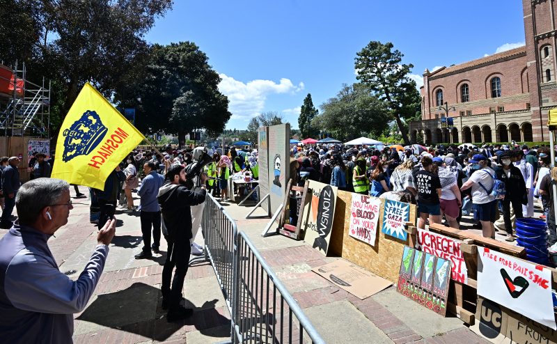 A Pro-Israel supporter waves a flag towards the encampment of Pro-Palestinian students on the campus of the University of California Los Angeles (UCLA), in Los Angeles on April 26, 2024. Pro-Palestinian protests spread to more college campuses in the United States on April 25, 2024 as authorities appeared to be running out of patience and police began to push back forcefully. Riot officers used chemical irritants and tasers at one university as administrators at some of the country's most prestigious institutions battled to prevent occupations taking hold. (Photo by Frederic J. BROWN / AFP) (Photo by FREDERIC J. BROWN/AFP via Getty Images)