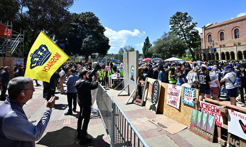 A Pro-Israel supporter waves a flag towards the encampment of Pro-Palestinian students on the campus of the University of California Los Angeles (UCLA), in Los Angeles on April 26, 2024. Pro-Palestinian protests spread to more college campuses in the United States on April 25, 2024 as authorities appeared to be running out of patience and police began to push back forcefully. Riot officers used chemical irritants and tasers at one university as administrators at some of the country's most prestigious institutions battled to prevent occupations taking hold. (Photo by Frederic J. BROWN / AFP) (Photo by FREDERIC J. BROWN/AFP via Getty Images)