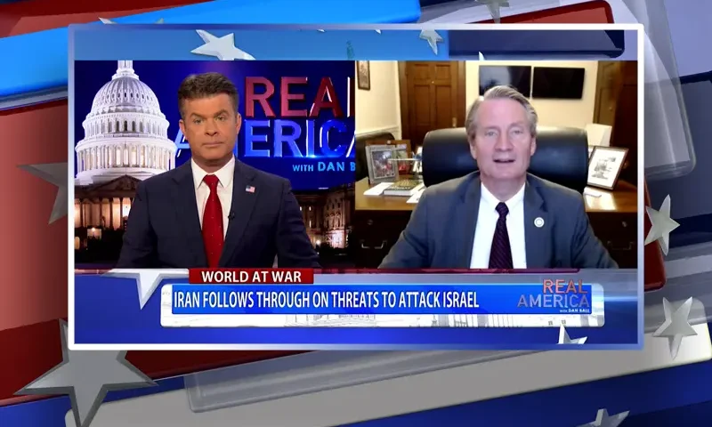 Video still from Real America on One America News Network showing a split screen of the host on the left side, and on the right side is the guest, Tim Burchett.