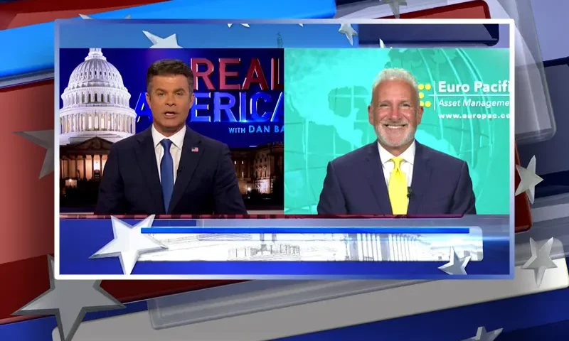 Video still from Real America on One America News Network showing a split screen of the host on the left side, and on the right side is the guest, Peter Schiff.