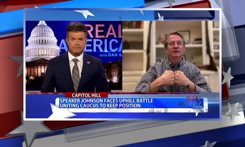 Video still from Real America on One America News Network showing a split screen of the host on the left side, and on the right side is the guest, Tim Burchett.