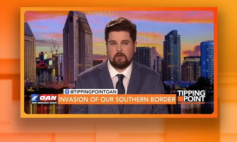 Video still of the host of Tipping Point at the desk of their talk show on One America News Network.