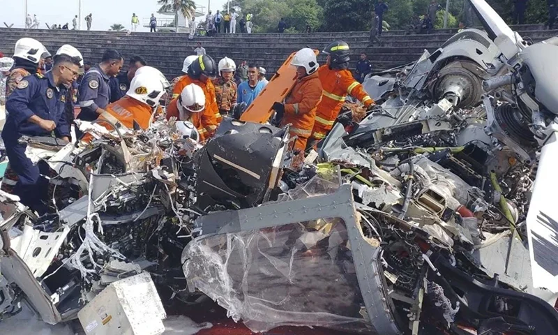 CORRECTS THE SOURCE - In this photo released by Fire & Rescue Department of Malaysia, fire and rescue department inspect the crash site of two helicopter in Lumur, Perak state, Monday, April 23, 2024. Malaysia's navy says two military helicopters collided and crashed during a training session, killing all 10 people on board. (Fire & Rescue Department of Malaysia via AP)